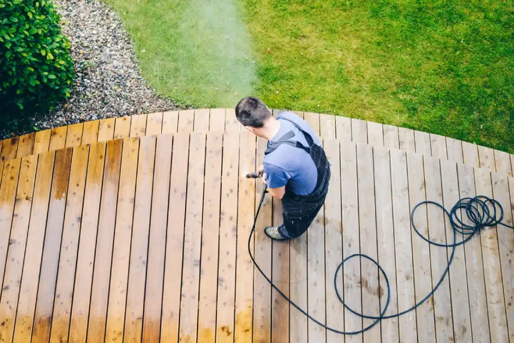 Handwerkservice Ferienhaus Småland Schweden ein Mann, der eine Holzterrasse besprüht